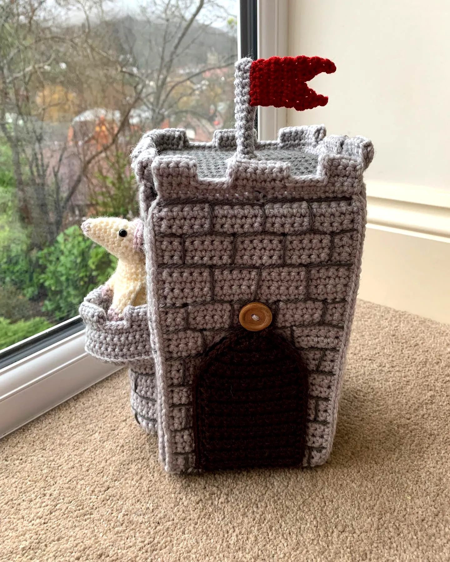 Adorable crochet castle in gray and brown with a red flag