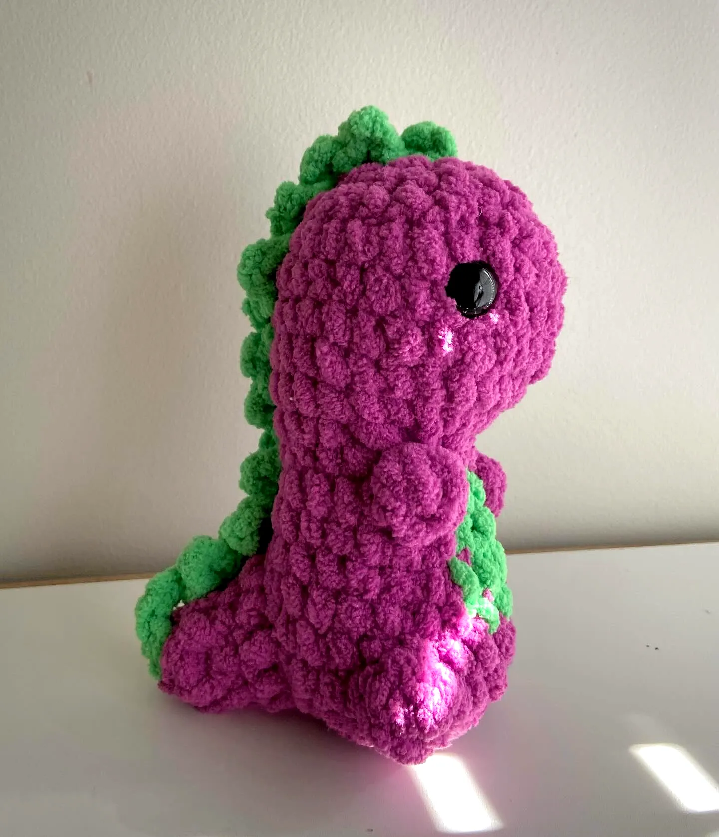 Adorable crochet dinosaur in vibrant purple and green hues