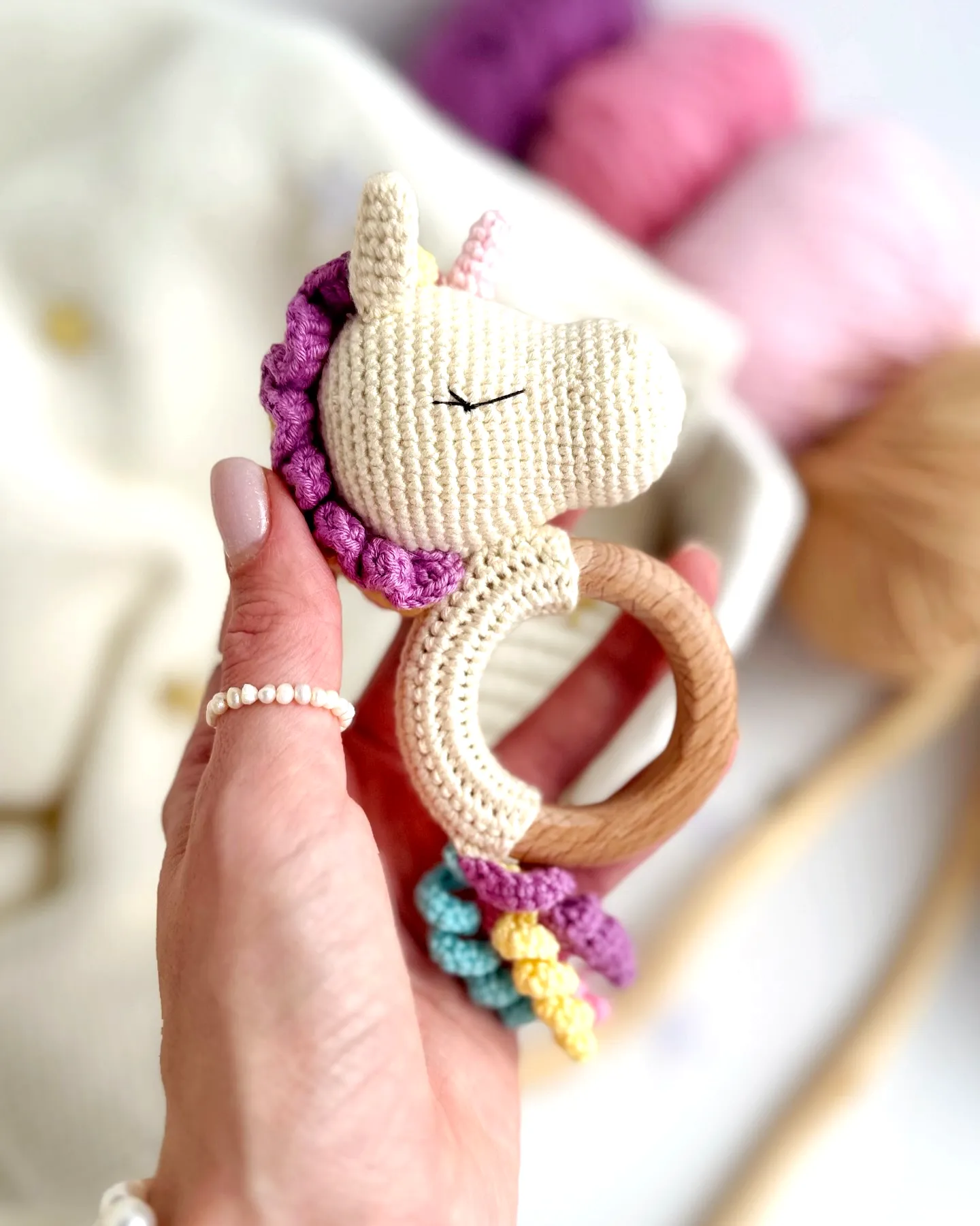Adorable crochet rattle in soft cream with vibrant unicorn accents