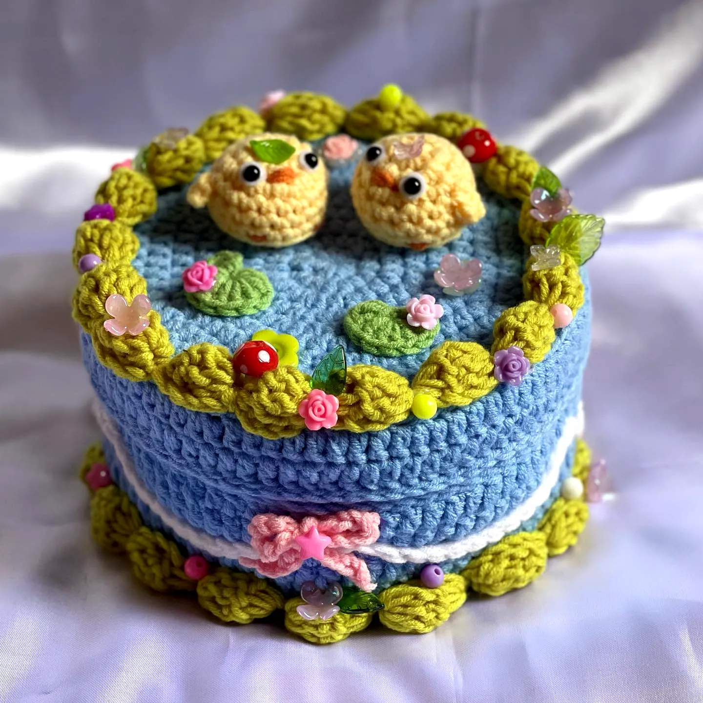 Charming Crochet Cake in Pastel Blue with Colorful Birds and Leaves