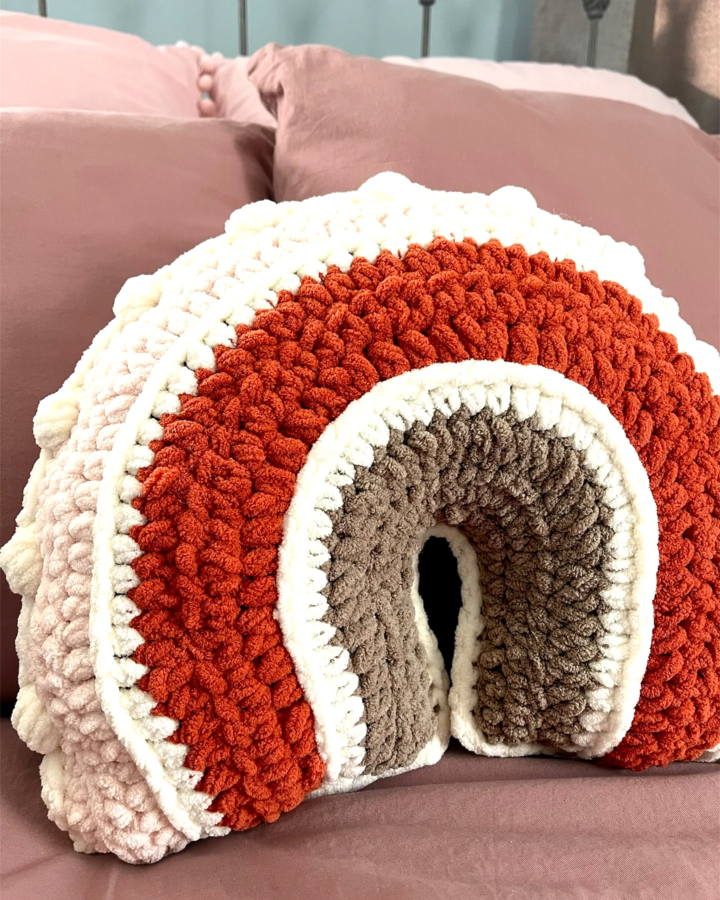 Colorful crochet pillow design with playful pom-pom edges