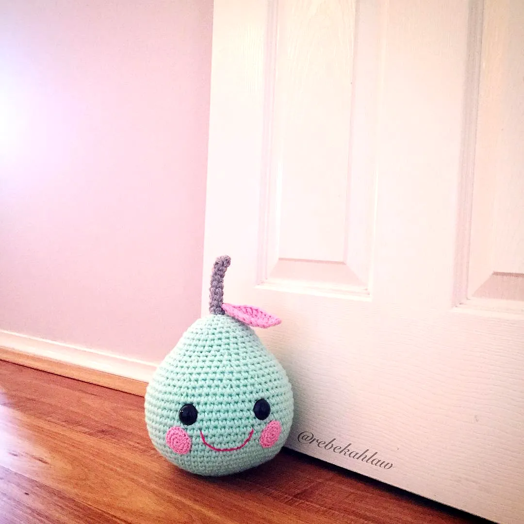 Cute mint green crochet doorstop with pink cheeks and leaf