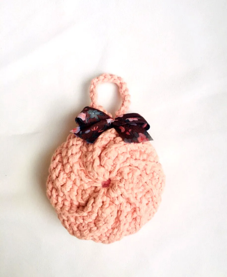 Cute pastel pink crochet face scrubber with floral bow detail