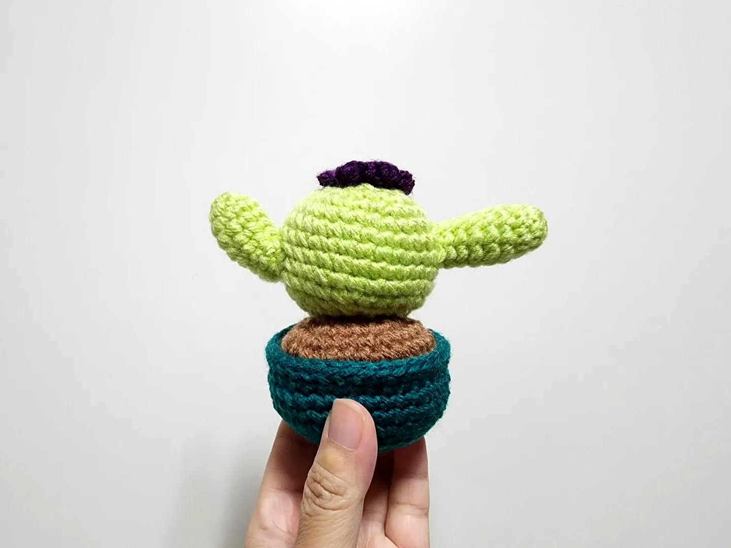 Cute vibrant crochet cactus with purple accents in a pot
