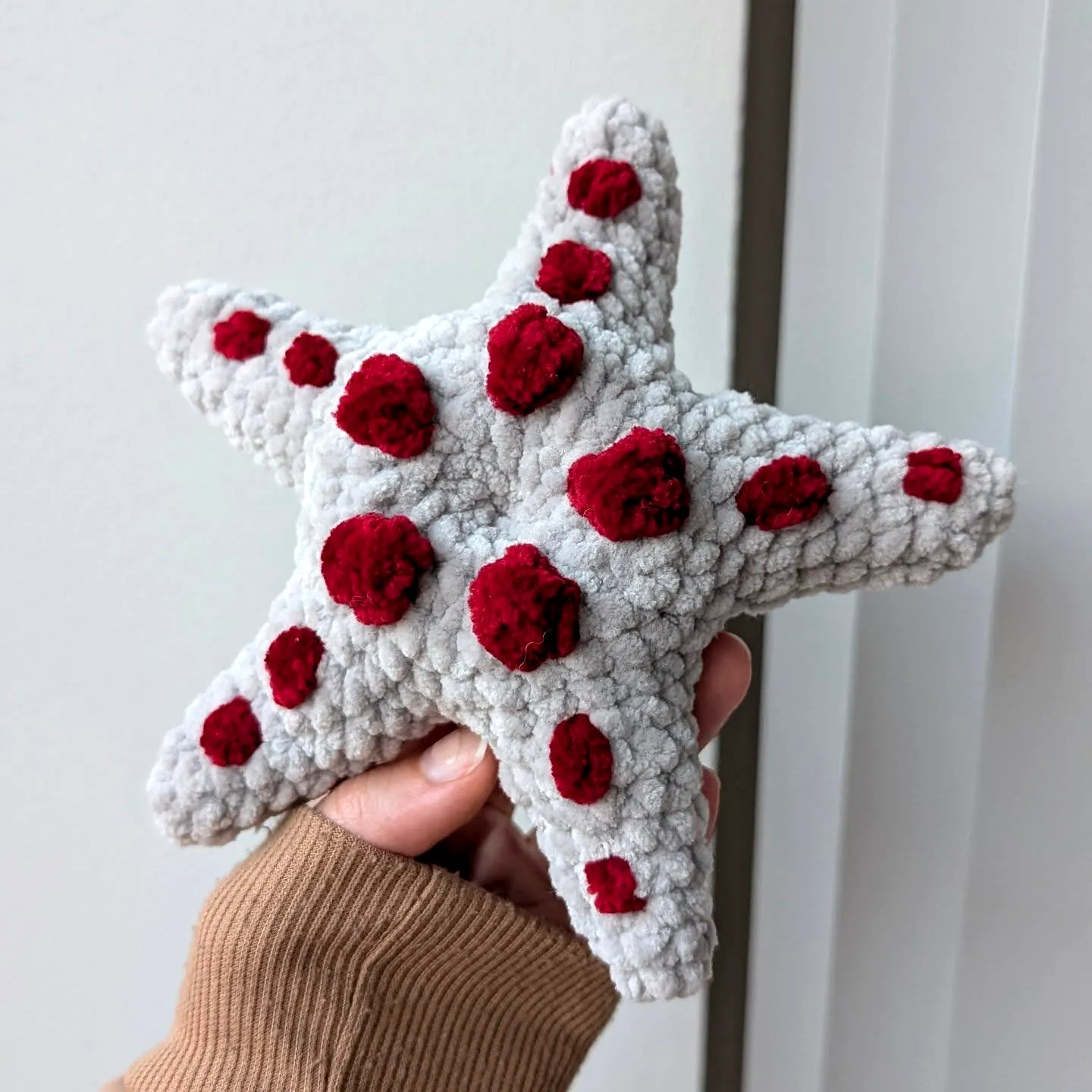 Delightful crochet starfish design in light gray with red spots